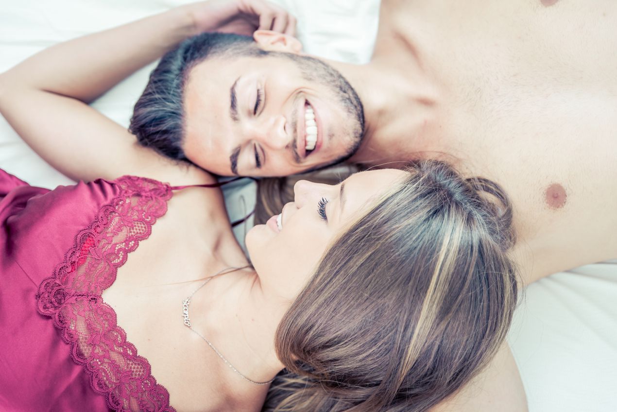 Lächelndes Paar im Bett symbolisiert emotionale Verbindung beim Escort München
